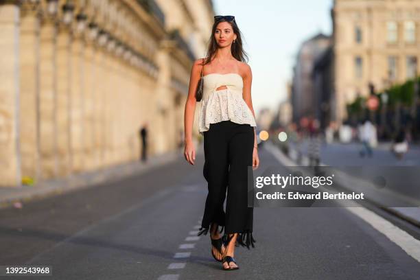 Amanda Derhy wears black sunglasses, gold and rhinestones pendant earrings from Dior, a gold chain pendant necklace, a white latte braided...