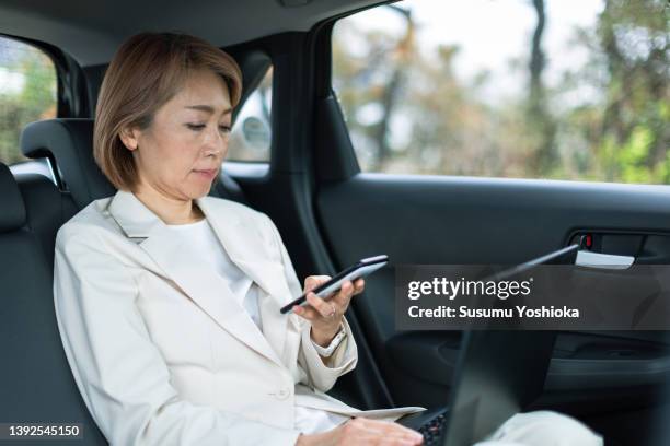 businesswoman sitting in the rear seat of a car - back seat stock pictures, royalty-free photos & images