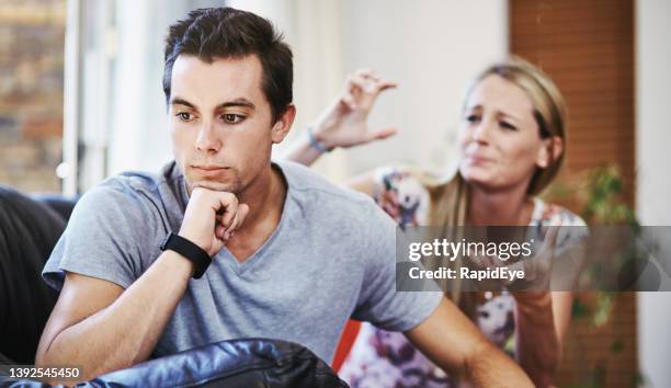 couple in trouble: man sulks, looking away, as woman gestures and pleads with him - pleading stock pictures, royalty-free photos & images