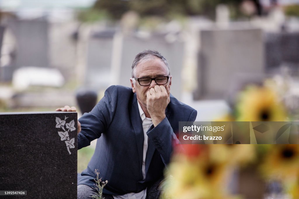 Middle-aged man in front of graves in a cemetery