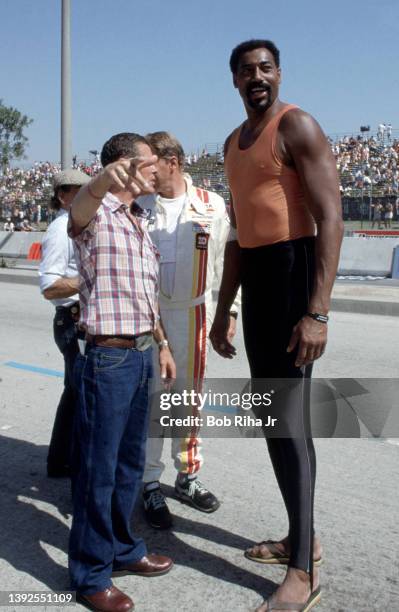 Racers Bobby Unser and Dan Gurney talk with NBA legend Wilt Chamberlain before the Toyota Long Beach Grand Prix race, April 13, 1985 in Long Beach,...