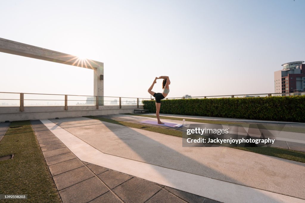 Woman stretching on yoga mat, at sunset