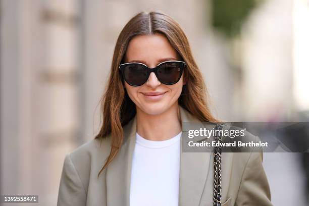 Diane Batoukina @diaanebt wears black sunglasses from Chanel, a white t-shirt, a beige gray oversized blazer jacket from Anine Bing, a black shiny...