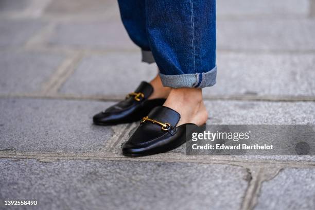 Diane Batoukina @diaanebt wears navy blue denim rolled-up large pants from Rouje, black shiny leather loafers mules from Massimo Dutti, during a...