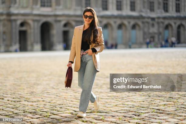 Sylvia Haghjoo wears black and brown print pattern sunglasses, a black asymmetric shoulder body top from Stella Mc Cartney, a beige long leather...