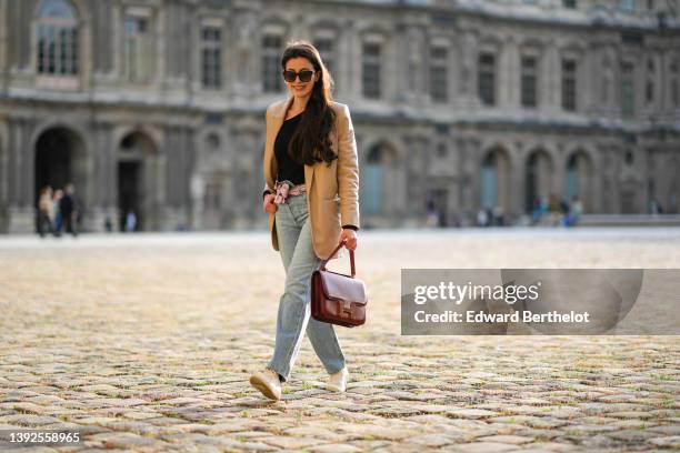 Sylvia Haghjoo wears black and brown print pattern sunglasses, a black asymmetric shoulder body top from Stella Mc Cartney, a beige long leather...