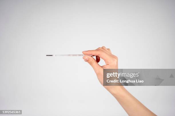 a woman holds a thermometer in her hand - temperature checkpoint stock pictures, royalty-free photos & images