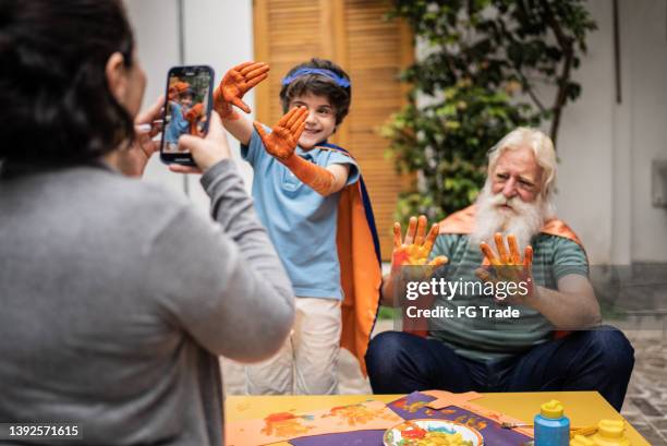 woman taking photos of boy and grandfather showing hands with paint - photographing garden stock pictures, royalty-free photos & images