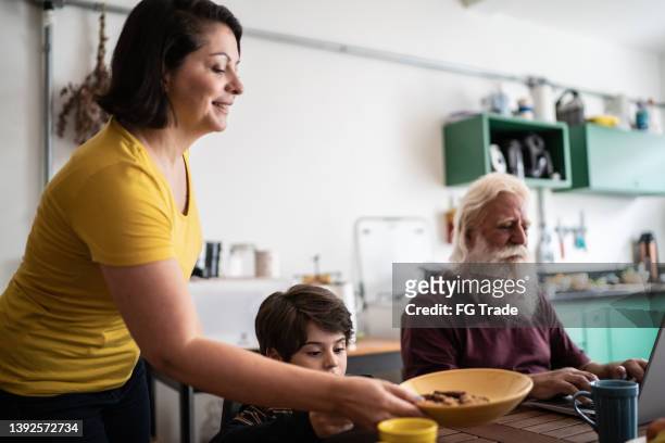 mãe servindo comida para filho e avô usando laptop em casa - grupo pequeno de pessoas - fotografias e filmes do acervo