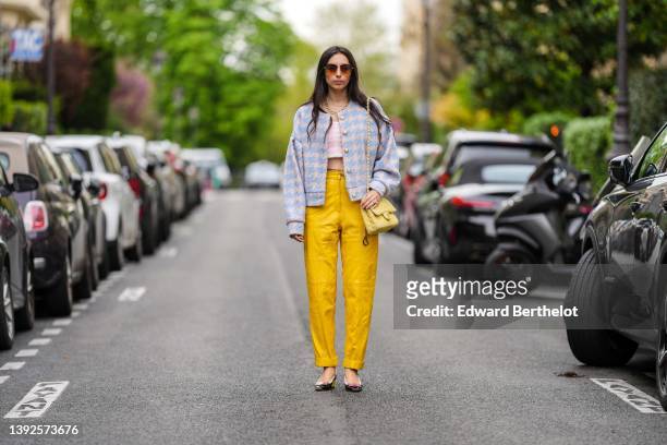 Gabriella Berdugo wears brown sunglasses, a gold large necklace, a silver chain necklace, a white and pale pink houndstooth print pattern wool...