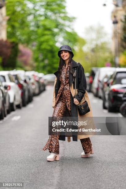 Gabriella Berdugo wears a black nylon bob hat from Maison Michel, a silver chain with diamond pendant necklace, a gold large chain necklace, a brown...