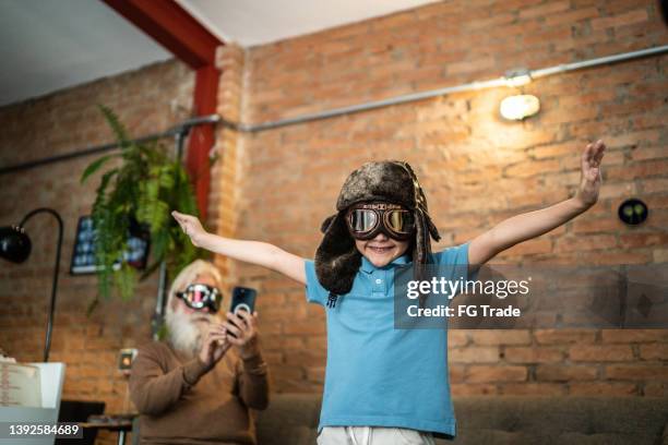 senior man filming grandson playing at home - aviation hat stock pictures, royalty-free photos & images