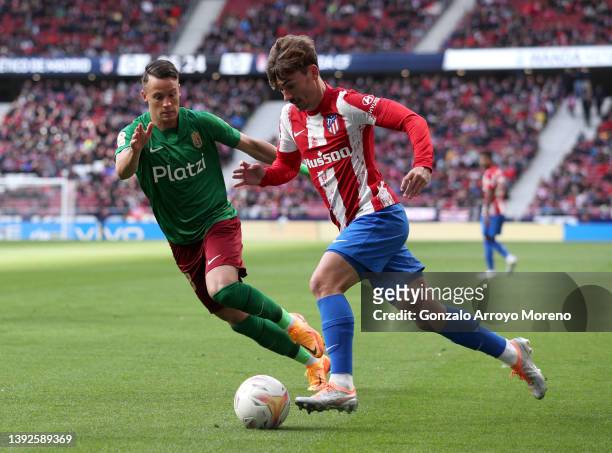 Antoine Griezmann of Atletico Madrid runs with the ball from Njegos Petrovic of Granada CF during the LaLiga Santander match between Club Atletico de...