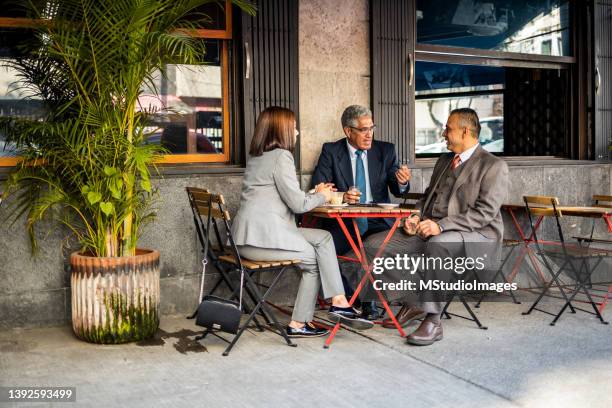 business meeting at cafe - 3 people at table talking stock pictures, royalty-free photos & images