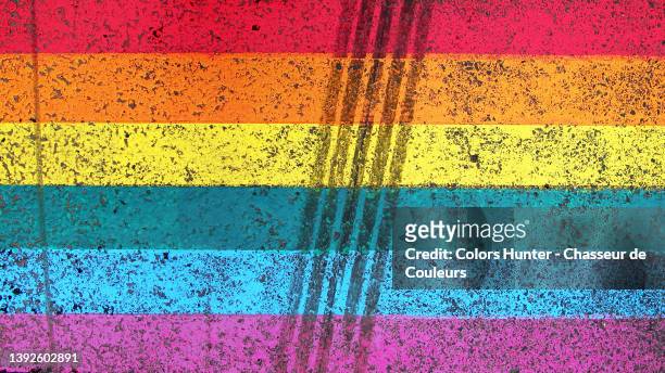 the rainbow flag of the lgbt community painted  on a street with tire track in paris - all love is equal fotos in paris stockfoto's en -beelden