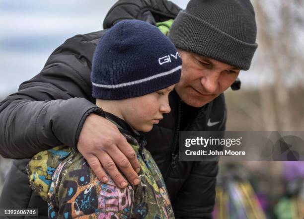 Father and son stand over the grave of their wife/mother during a funeral on April 20, 2022 in Bucha, Ukraine. Hundreds of Ukrainians killed during...