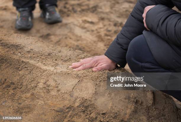 Husband touches the soil on the grave of his wife on April 20, 2022 in Bucha, Ukraine. Hundreds of Ukrainians killed in the Russian invasion in Bucha...