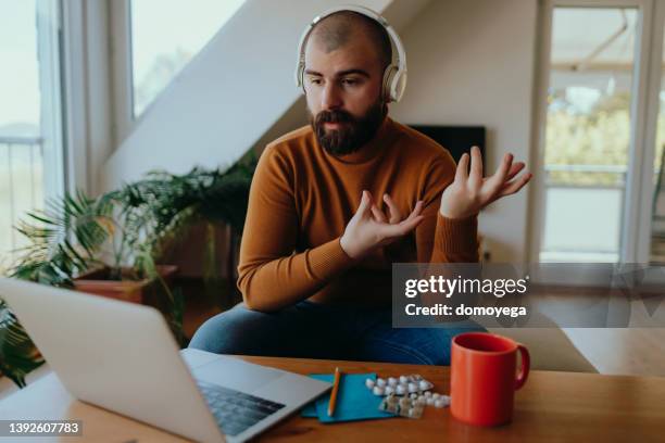 young man having an online therapy session from home - online therapy stock pictures, royalty-free photos & images
