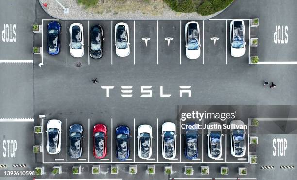 In an aerial view, Tesla cars sit parked in a lot at the Tesla factory on April 20, 2022 in Fremont, California. Tesla reported first quarter...