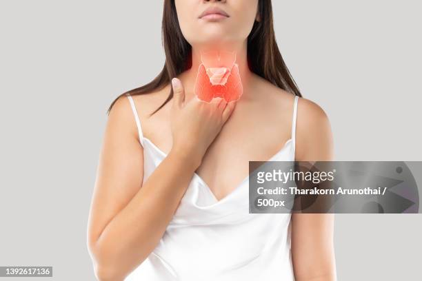 thyroid gland control,midsection of woman holding condom against white background - tonsille stock-fotos und bilder