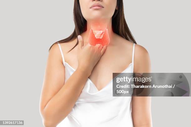 thyroid gland control,midsection of woman holding condom against white background - schildklier stockfoto's en -beelden