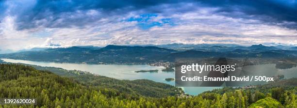 cloudy view on lake worth,austria,panoramic view of landscape and mountains against sky - carinthia stock pictures, royalty-free photos & images