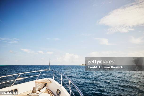 medium wide shot of bow of yacht approaching deserted tropical island - schiffsbug stock-fotos und bilder
