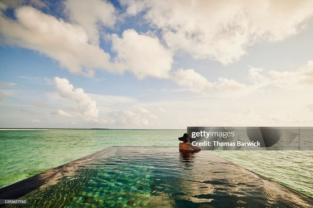 Extreme wide shot of mature woman relaxing in infinity pool