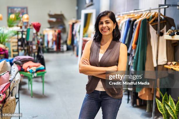 latin american female dress store owner standing with arms crossed looking at the camera - clothing store stock pictures, royalty-free photos & images