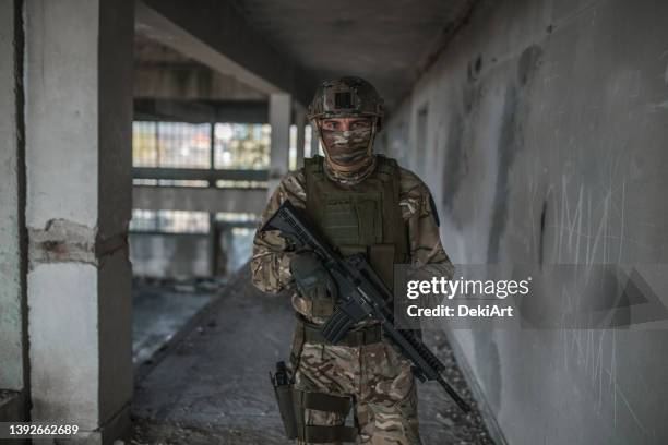 unrecognizable soldier armed with rifle in camouflage uniform in conflict zone - special forces stockfoto's en -beelden