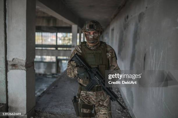 unrecognizable soldier armed with rifle in camouflage uniform in conflict zone - forças armadas especiais imagens e fotografias de stock