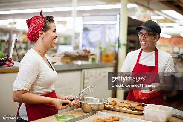 young woman and man laughing in commercial kitchen - baker occupation stock pictures, royalty-free photos & images