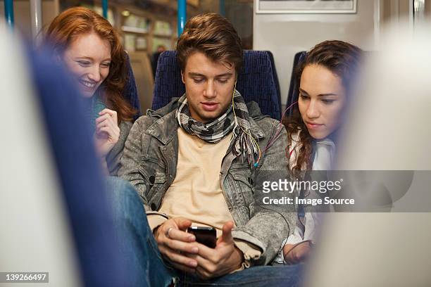 three young friends travelling on train listening to music - railroad car stock-fotos und bilder