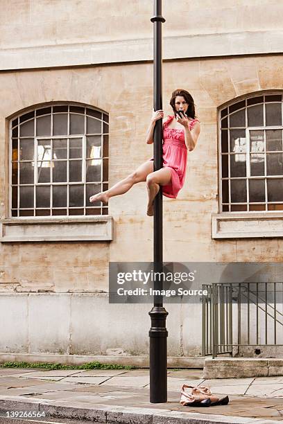 mitte erwachsene frau im rosa kleid mit cellphone auf street - akrobatik stock-fotos und bilder