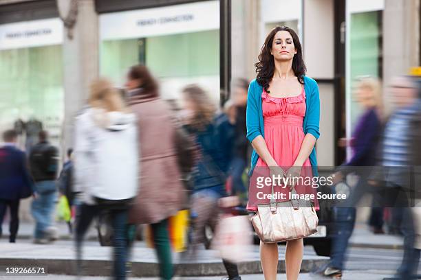 mid adult woman in pink dress standing still in crowded city - être à l'arrêt photos et images de collection