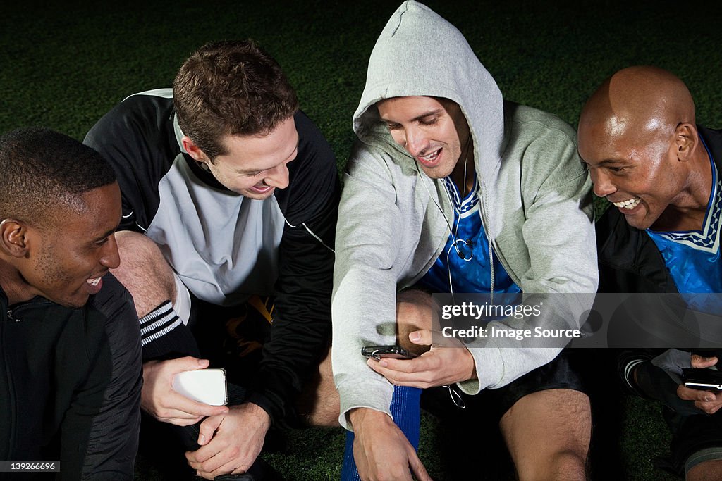Soccer players looking at cellphone on pitch