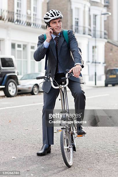 mid adult businessman using cellphone on bicycle - folding bike stockfoto's en -beelden