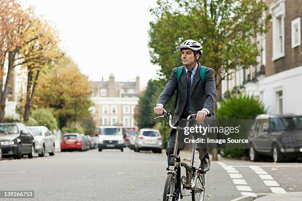 mid adult businessman riding bicycle on street - folding bike stockfoto's en -beelden