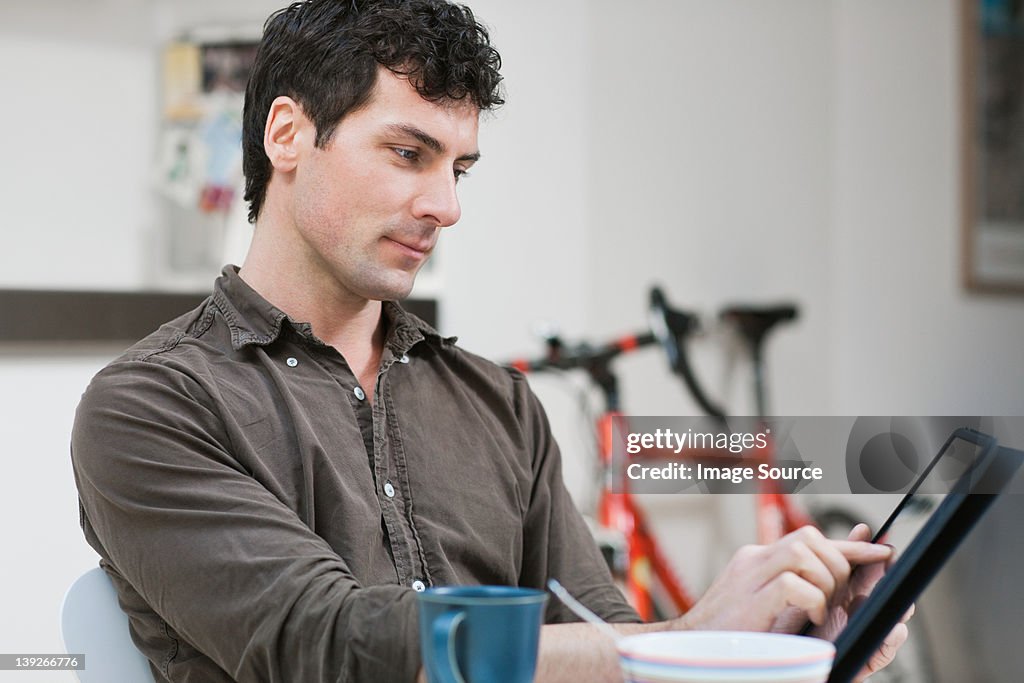 Mid adult man using digital tablet at home