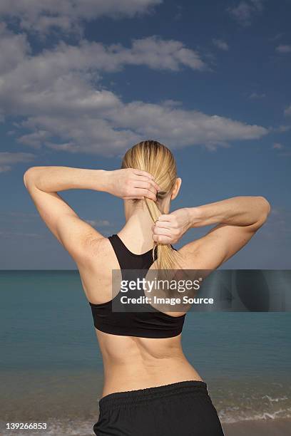 mid adult woman tying ponytail, rear view - strong hair 個照片及圖片檔