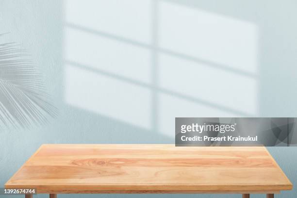shadow on a blue concrete walls with wooden table - table stock pictures, royalty-free photos & images