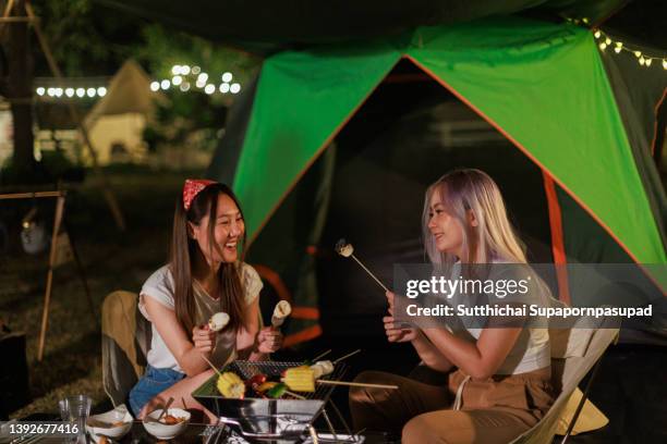 two asian female having a barbeque steak outside while camping. - barbeque party woman stock-fotos und bilder