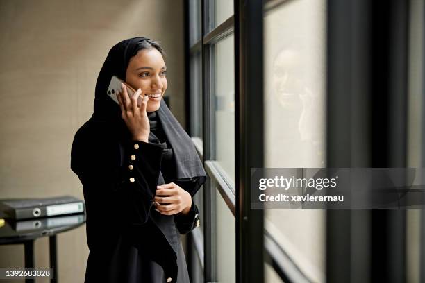 smiling young saudi businesswoman using phone - saudi women stock pictures, royalty-free photos & images