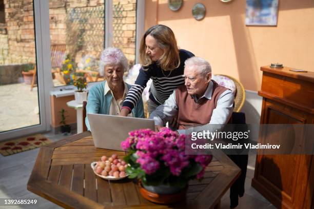 home carer helping senior couple with online shopping - paying doctor stock pictures, royalty-free photos & images