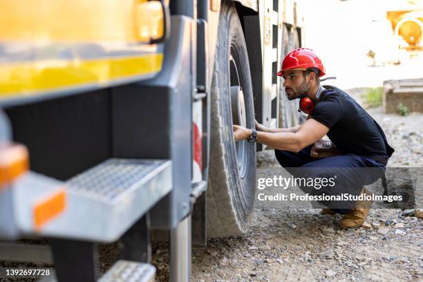 un trabajador mecánico está revisando el neumático de un camión. - maquinaria de construcción fotografías e imágenes de stock