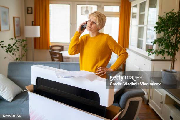 a cosumer making a phone call regarding her new purchase - damaged parcel stock pictures, royalty-free photos & images