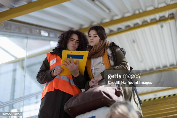 volunteer giving information to ukrainian refugee woman at train station. - humanitarian aid stock pictures, royalty-free photos & images