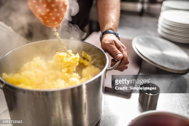 a chef in a restaurant kitchen mixes potatoes into mashed potatoes. - stuffed potato stock pictures, royalty-free photos & images