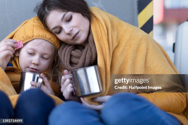 ukrainian immigrants mother with daughter with luggage waiting at train station wrapped in blanket - displaced stock pictures, royalty-free photos & images