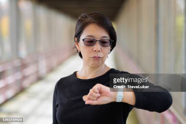 mujer enojada que comprueba la hora - impatient fotografías e imágenes de stock